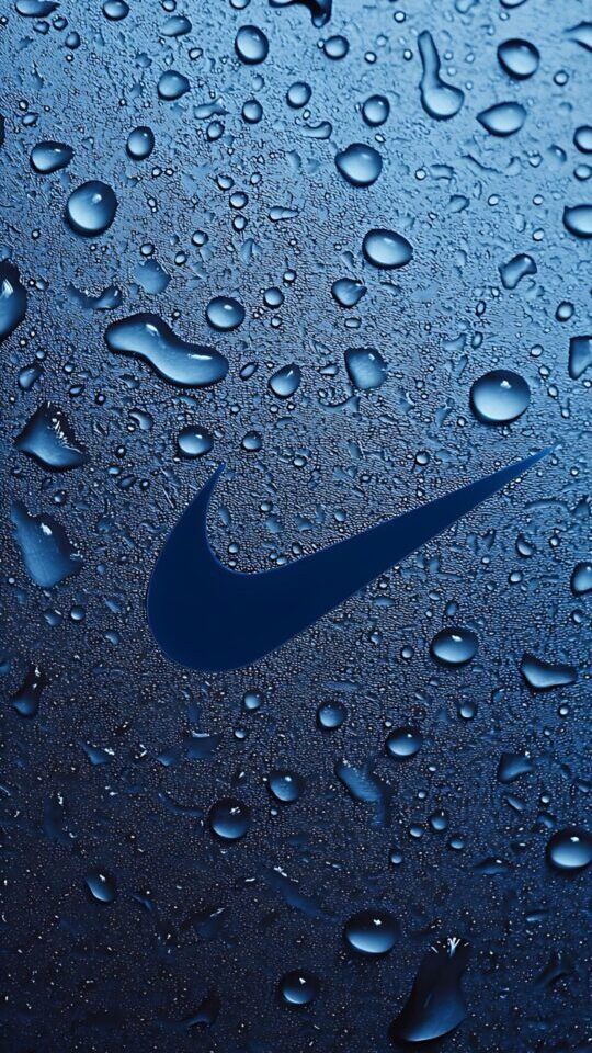 A detailed close-up shot of the Nike Swoosh logo on a dark blue surface. The surface is covered in a dense pattern of water droplets of different sizes, which catch the light and create a textured, glossy effect.