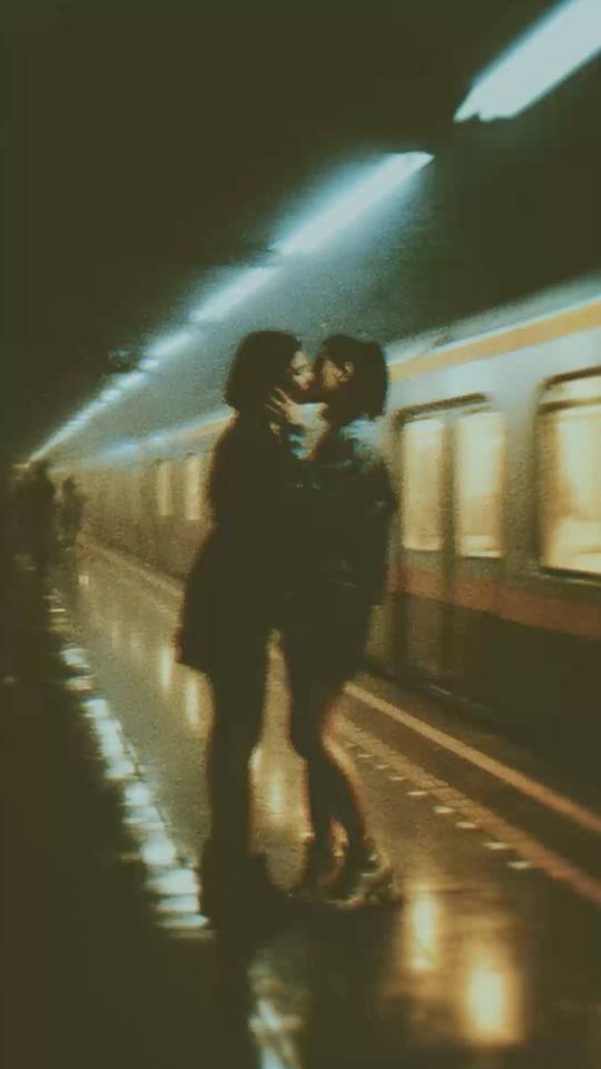 Two girls kissing on a subway platform